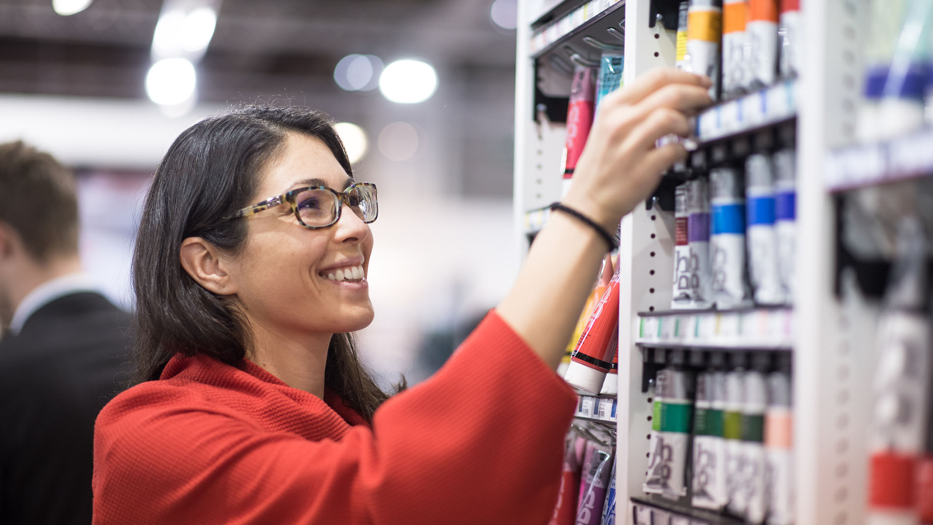Woman takes a tube of watercolour paint from the shelf at Creativeworld